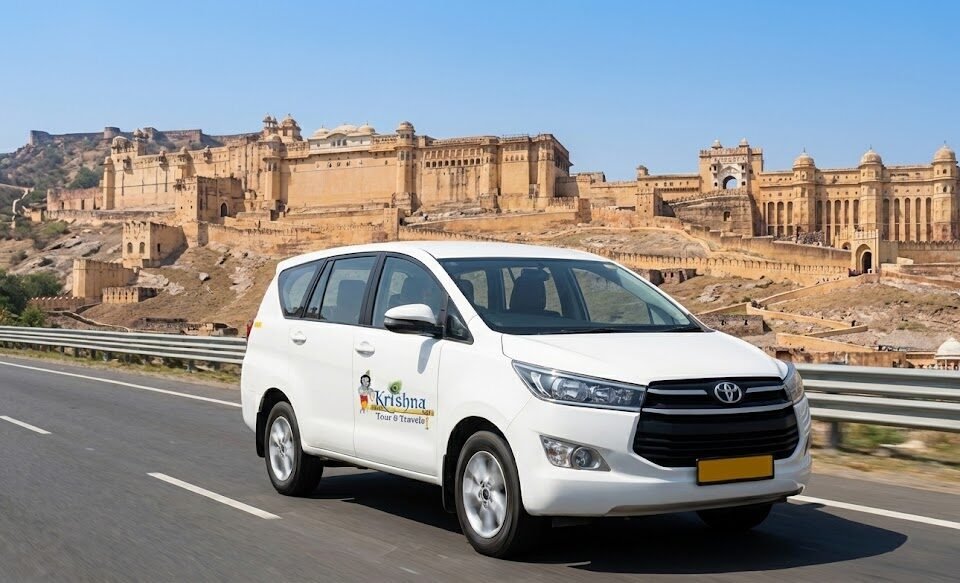 a shri krishna tour & travels taxi on a highway in rajasthan, with a majestic fort in the background.
