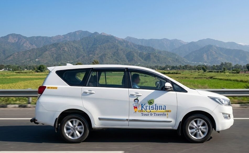a shri krishna tour and travels innova taxi cruises on a highway, with green fields and the himalayan foothills visible in the background, en route to haridwar.