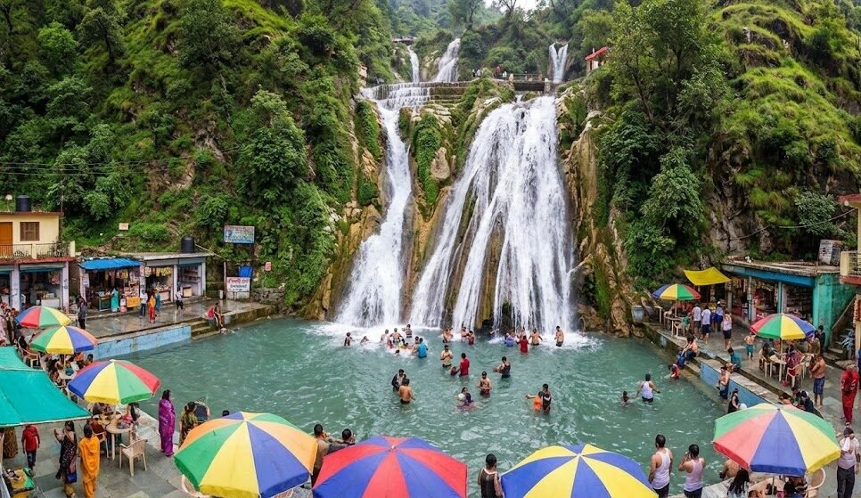 a panoramic view of kempty falls in mussoorie, with visitors bathing in the pool below the cascading waterfall.
