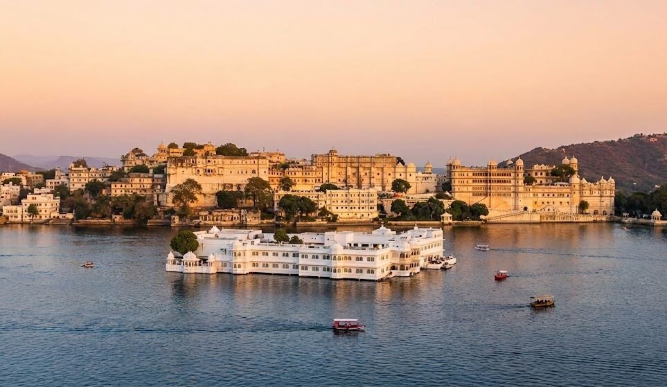 Noida to Jaipur Taxi Service with Udaipur Tour Options a scenic sunset view of lake pichola in udaipur, featuring the white lake palace (taj lake palace) in the water and the city palace complex on the shore.